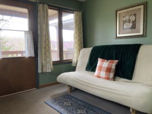 beige queen futon with pillow and blanket in green room