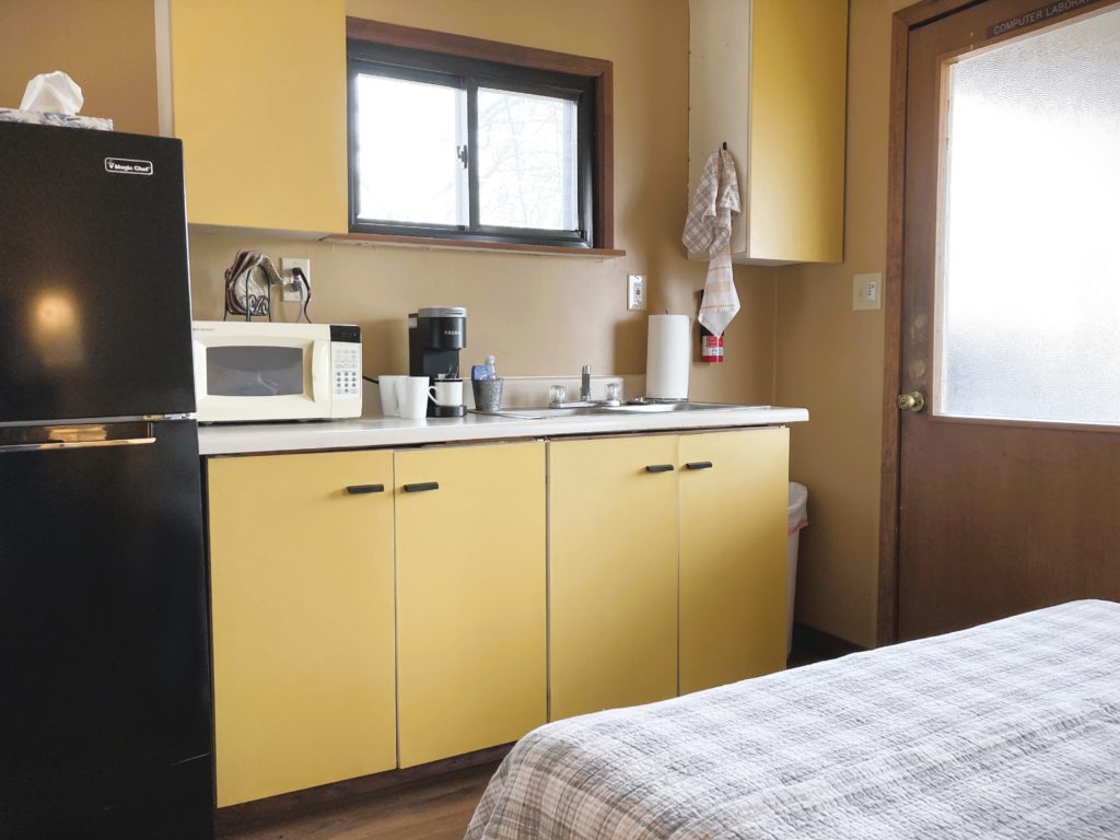 yellow kitchenette with fridge sink microwave