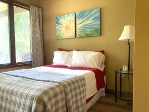 full sized bed with gray plaid quilt in yellow room
